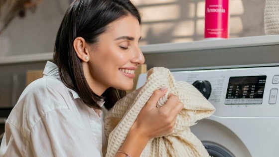 A smiling woman enjoying the fresh scent of clean laundry, highlighting the benefits of choosing the right LG WashCombo or WashTower for a Miami condo.