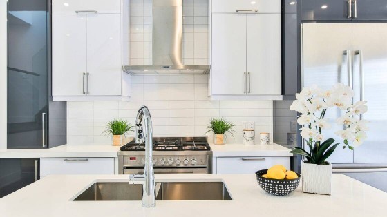 A luxury modern kitchen featuring high-gloss cabinetry, a professional-grade stainless steel range, and a sleek ventilation hood, representing the integration of AI-powered appliances in cont